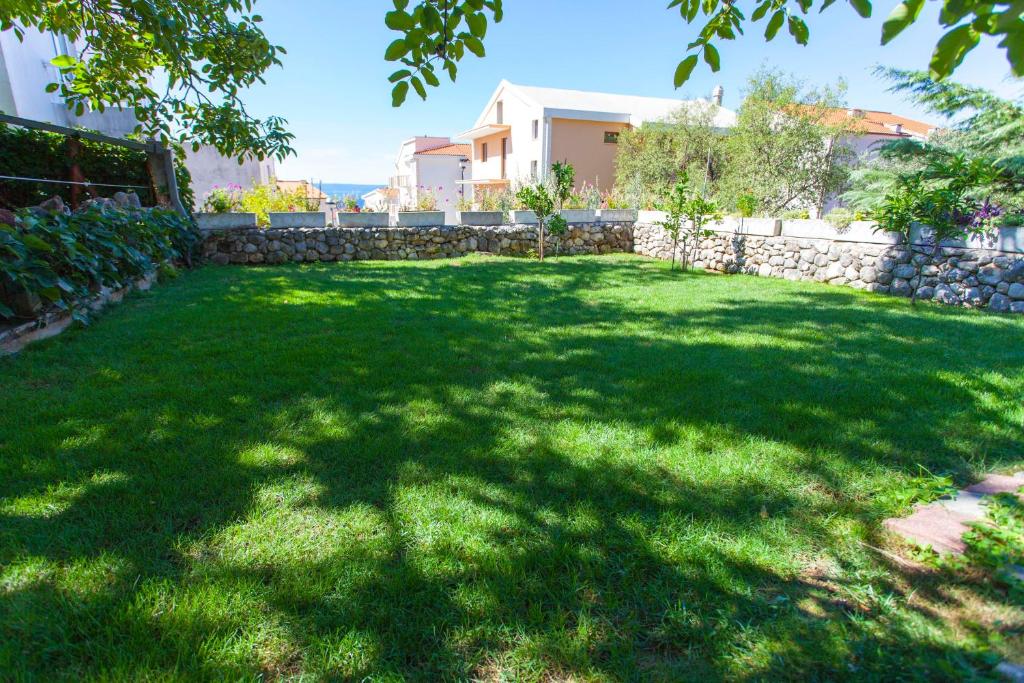 un gran patio con una pared de piedra y césped verde en Apartments Paunovic, en Makarska