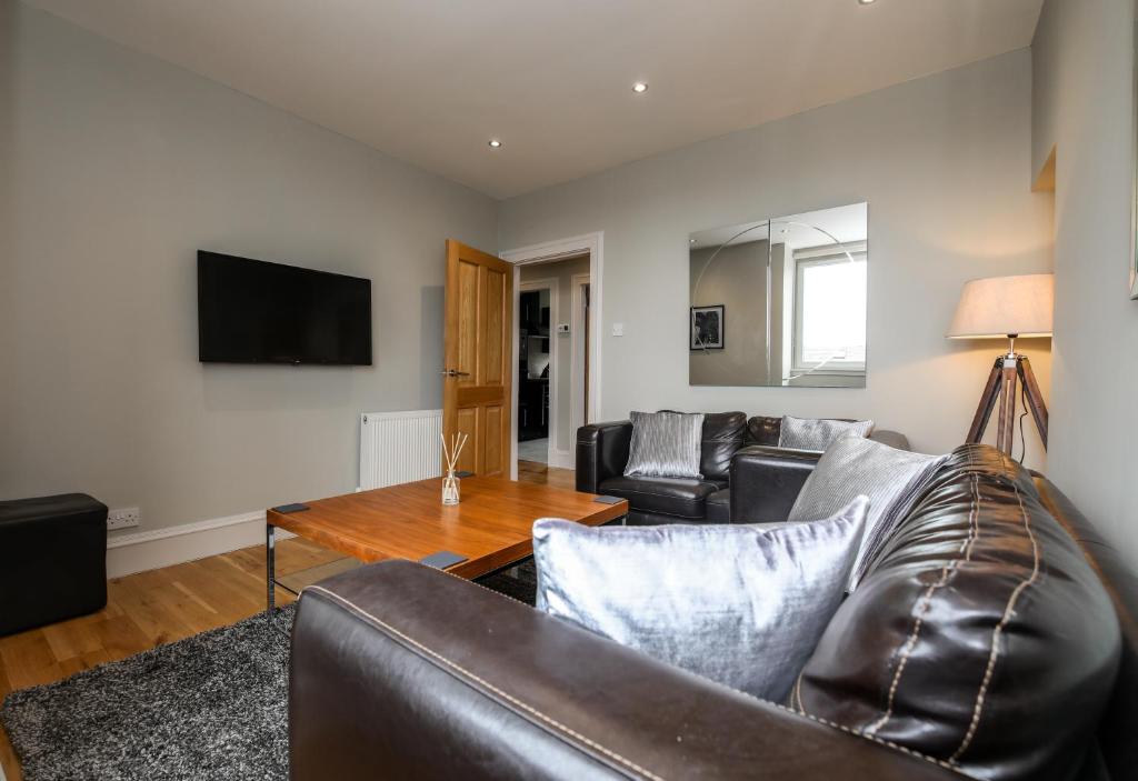 sala de estar con sofá de cuero y mesa en Apartment F, en Aberdeen