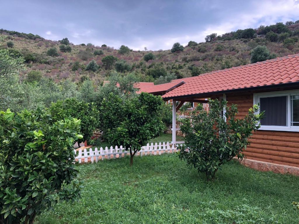 a house with a fence and two trees in the yard at The Mussel House in Ksamil