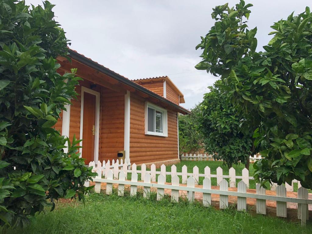 una casa in legno con una staccionata bianca di The Mussel House a Ksamil