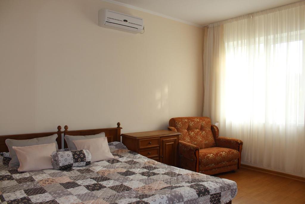 a bedroom with a bed and a chair at Guest House on Turgeneva 188 in Anapa