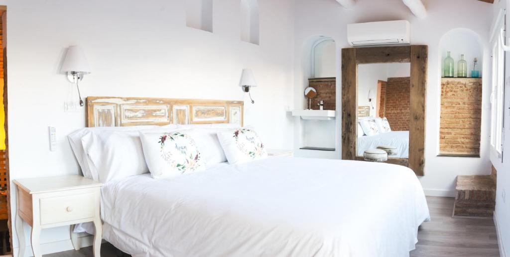 Dormitorio blanco con cama blanca y espejo en PINTORES ROOMS Apartamentos Turísticos, en Cáceres