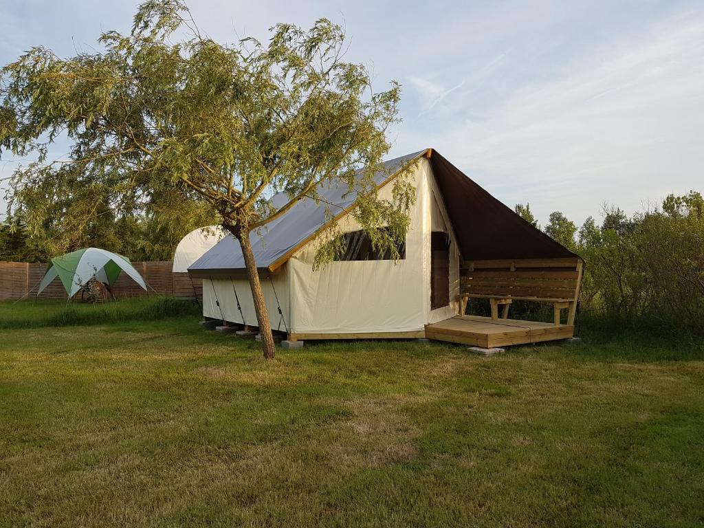 une grande tente dans un champ avec un arbre dans l'établissement Camping Les Chagnelles, au Perrier