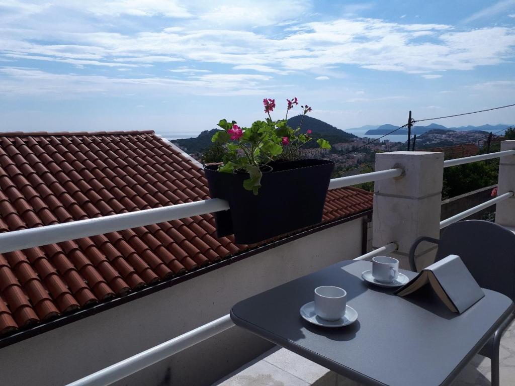 una mesa con dos tazas y un libro en el balcón en Alto Rooms and Apartments, en Dubrovnik