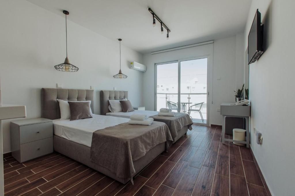 a bedroom with two beds and a balcony at River View Boutique Apts in Ayia Napa