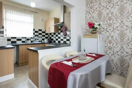 uma cozinha com uma mesa com uma toalha de mesa vermelha em KNUTSFORD House Holidays em Manchester