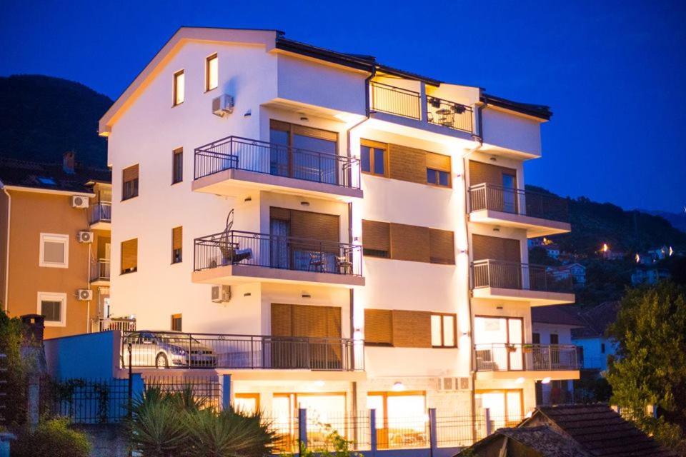 a large white building with a car in front of it at Porto Apartmani in Tivat