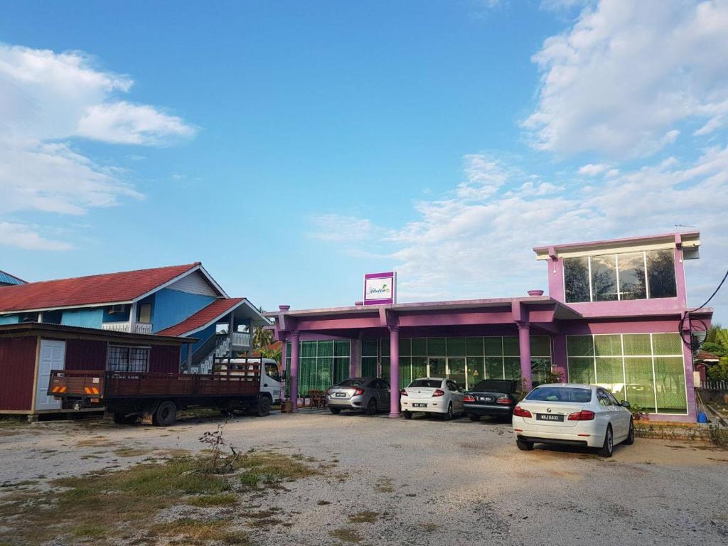 a building with cars parked in a parking lot at Paka Tamim Seaview Hotel in Paka