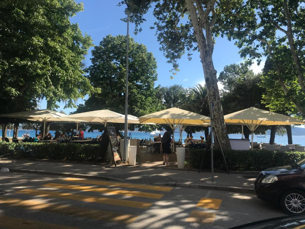 eine Gruppe von Tischen mit Sonnenschirmen neben dem Wasser in der Unterkunft Luxury Town Center Apartments in Zadar