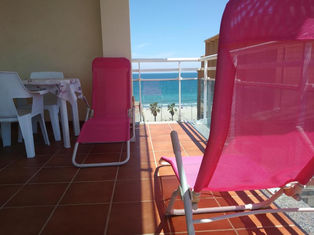 ペニスコラにあるAda Neptuno Apartamento, junto a la playa, Aire acondicionado, Parking, WiFi, Piscinasのピンクの椅子、ビーチを望むバルコニーが備わる客室です。