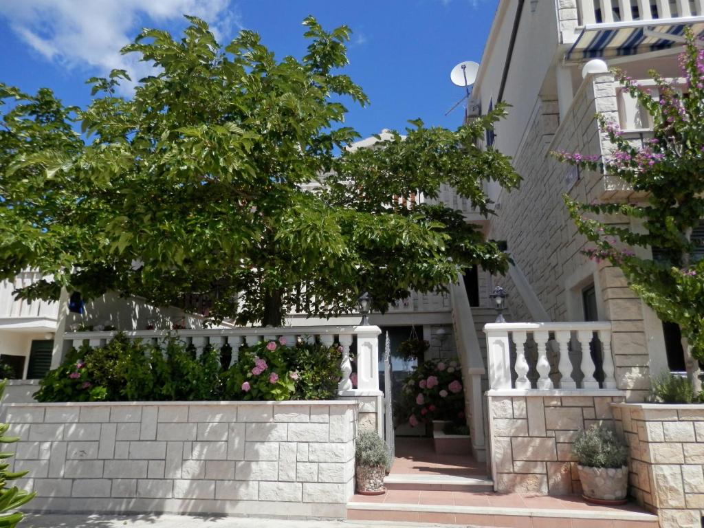 une clôture blanche devant une maison fleurie dans l'établissement Apartments Hrgovic, à Rogoznica