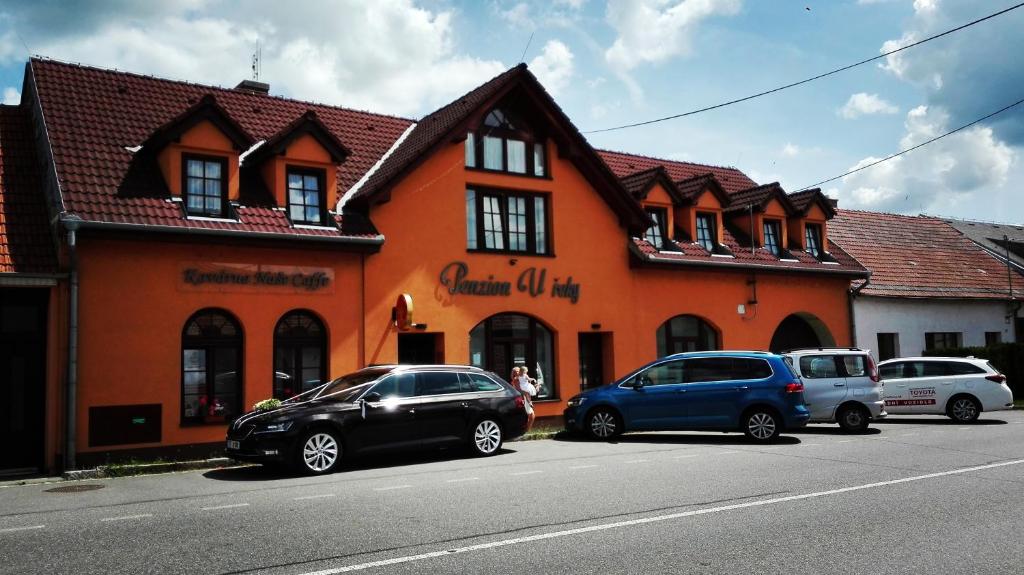 two cars parked in front of a orange building at Penzion U řeky in Vojkovice