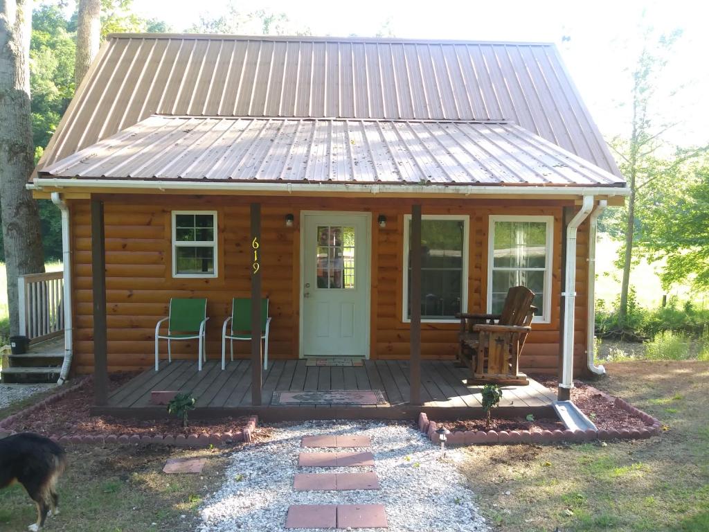 a log cabin with a porch and two chairs at Tranquil Waters Cabin in Frenchburg
