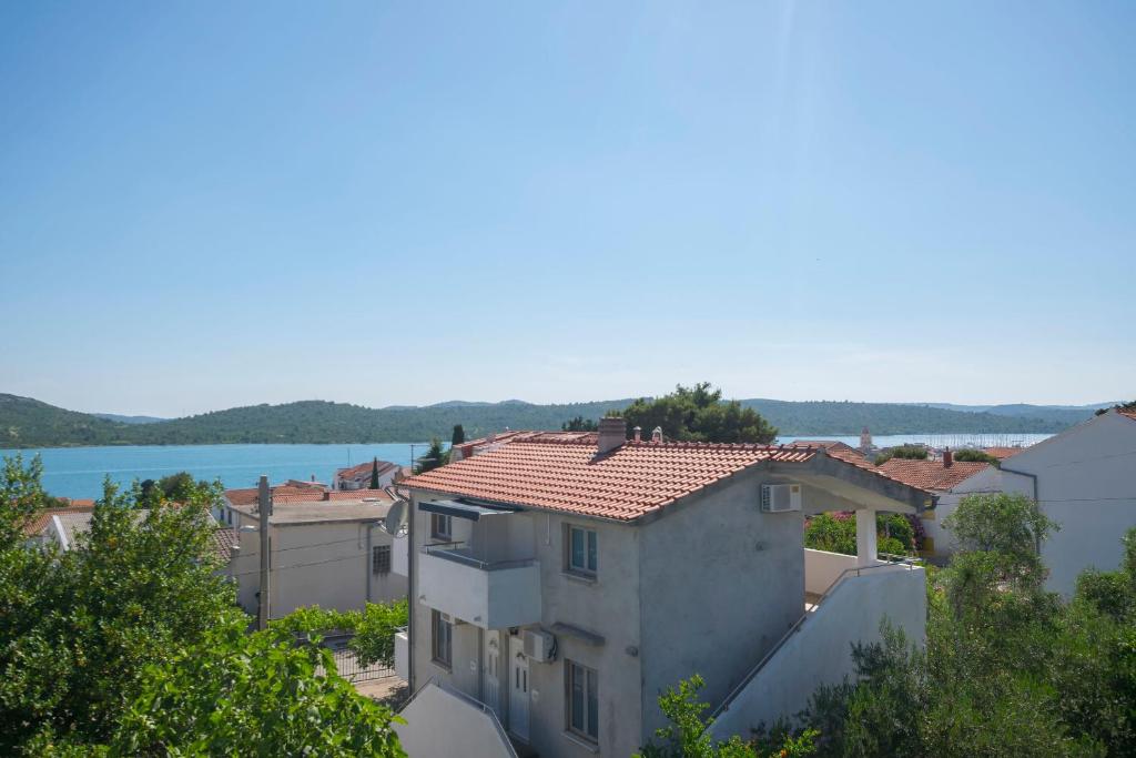 a white house with a red roof and a lake at Apartments Katarina in Pirovac