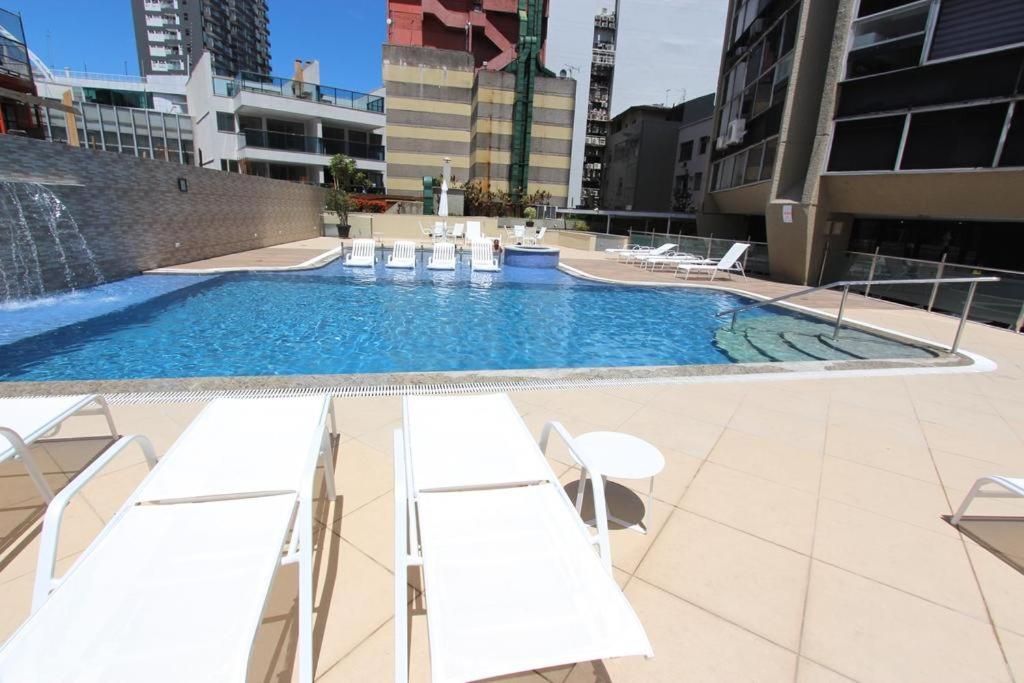 una piscina con tumbonas blancas en un edificio en Apartamento Leblon - Rio Design, en Río de Janeiro