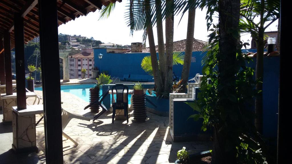 a patio with palm trees and a swimming pool at HOTEL pousada CASARÃO in Serra Negra
