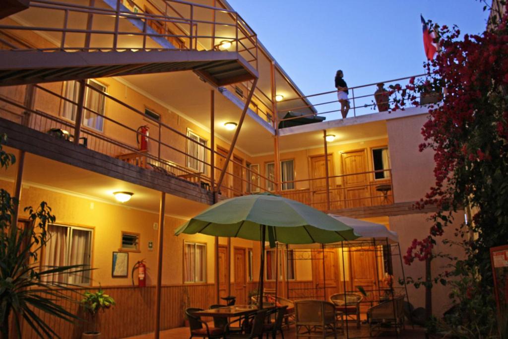 a building with a patio with a green umbrella at Hotel CostaFósil in Caldera