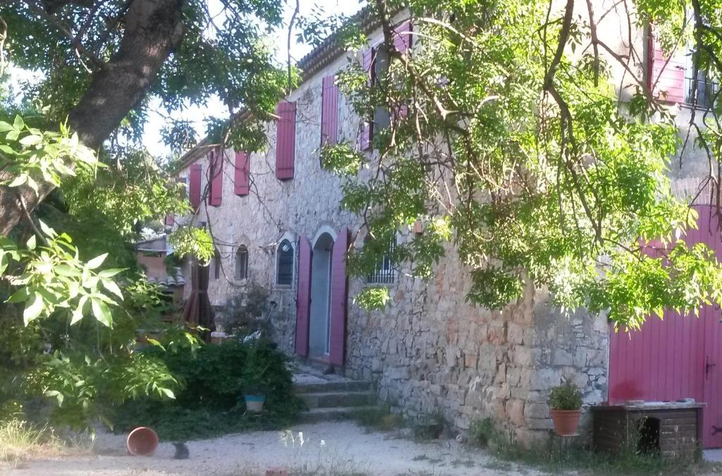 una antigua casa de piedra con puertas rosas y árboles en Joli T2 1er etage ancienne bergerie, en La Seyne-sur-Mer
