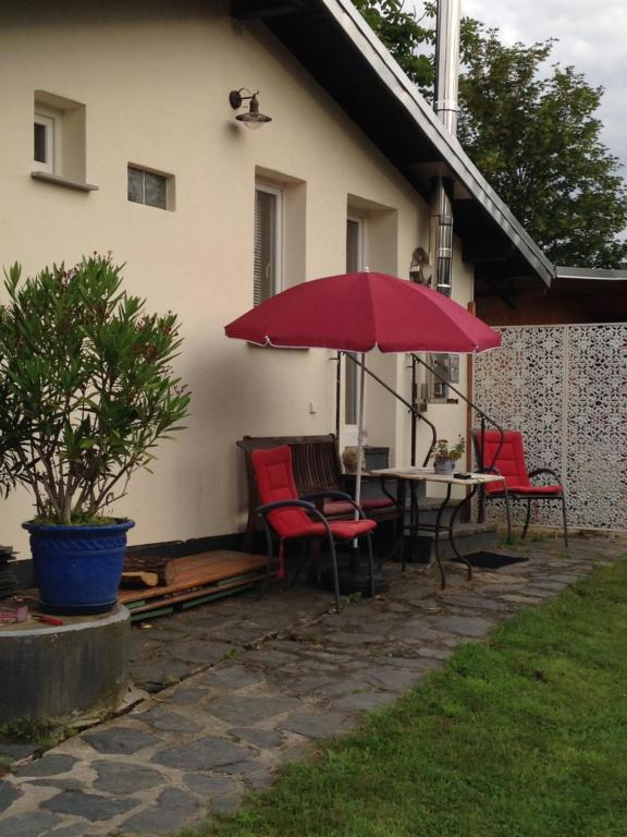 een patio met een tafel en stoelen en een rode parasol bij Künstlerhäuschen in Oberwesel