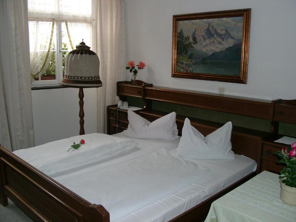 ein Bett mit weißer Bettwäsche und einer Blume darauf in der Unterkunft Gasthaus Löwen in Freiburg im Breisgau