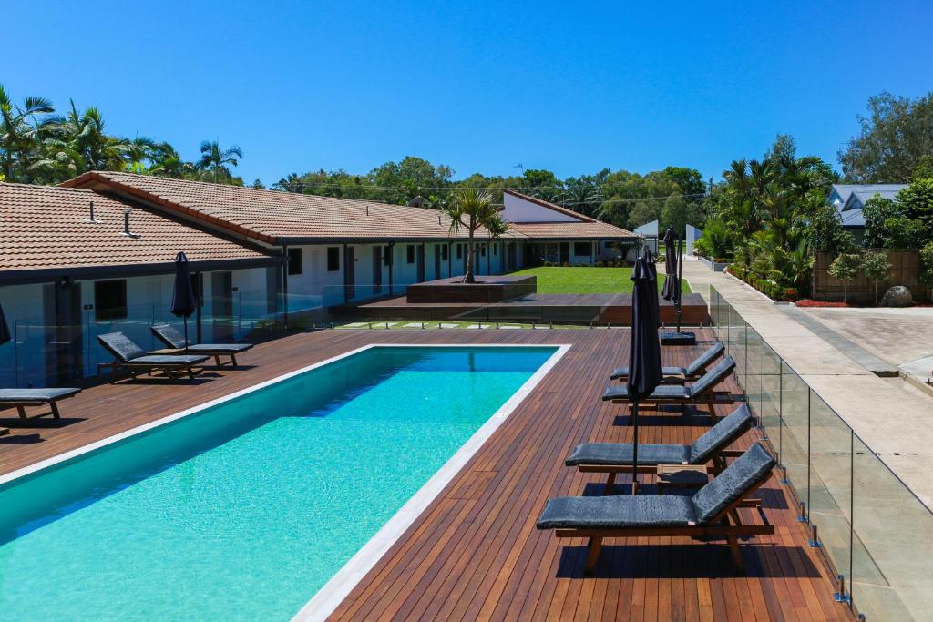 a swimming pool with lounge chairs next to a house at Birch Resort Port Douglas in Port Douglas