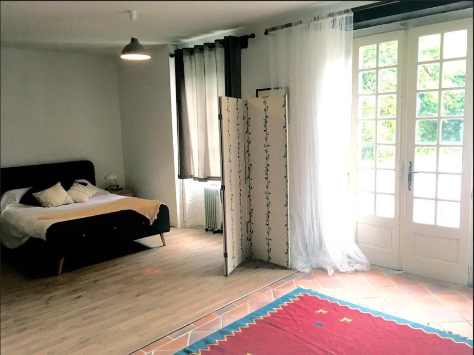 - une chambre avec un lit et une grande fenêtre dans l'établissement Maison Lyre, Pompadour, à Arnac-Pompadour