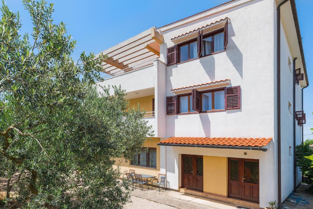 a white building with brown windows and a tree at Apartment Promona Drniš in Drniš