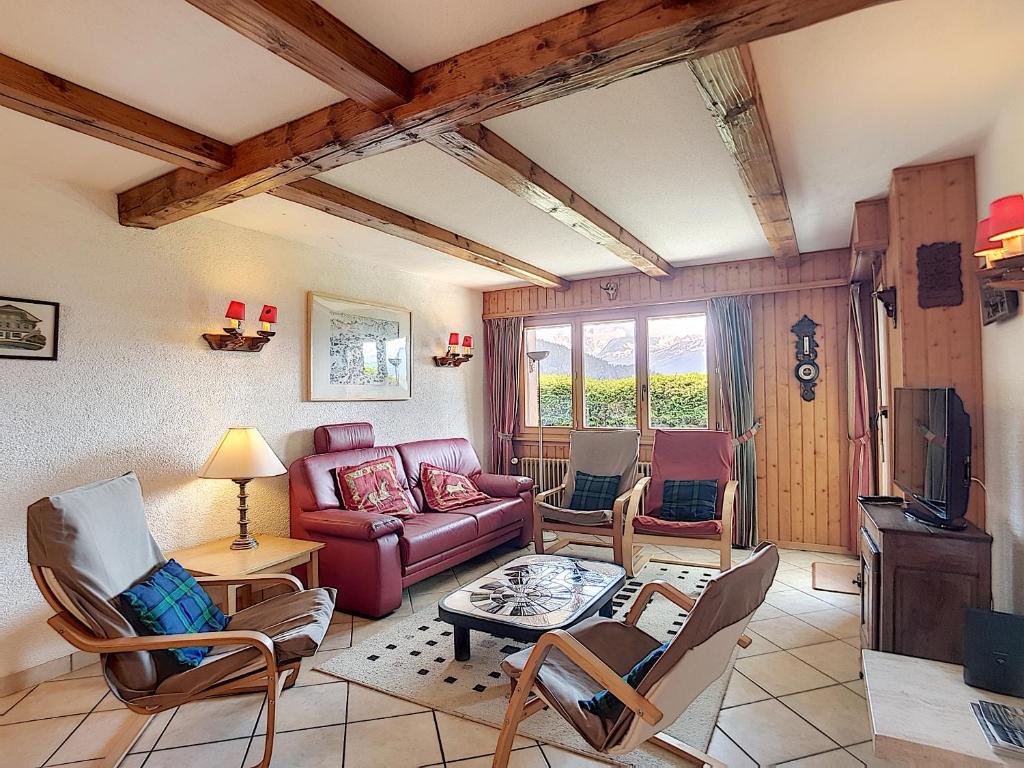 een woonkamer met een bank en stoelen en een tv bij Boucanier 002, appartement avec jardin in Verbier