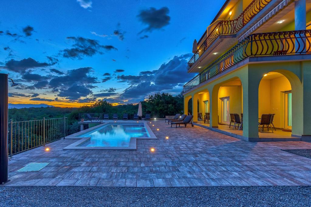 a villa with a swimming pool at dusk at Luxury apartments Kostrena with pool in Kostrena