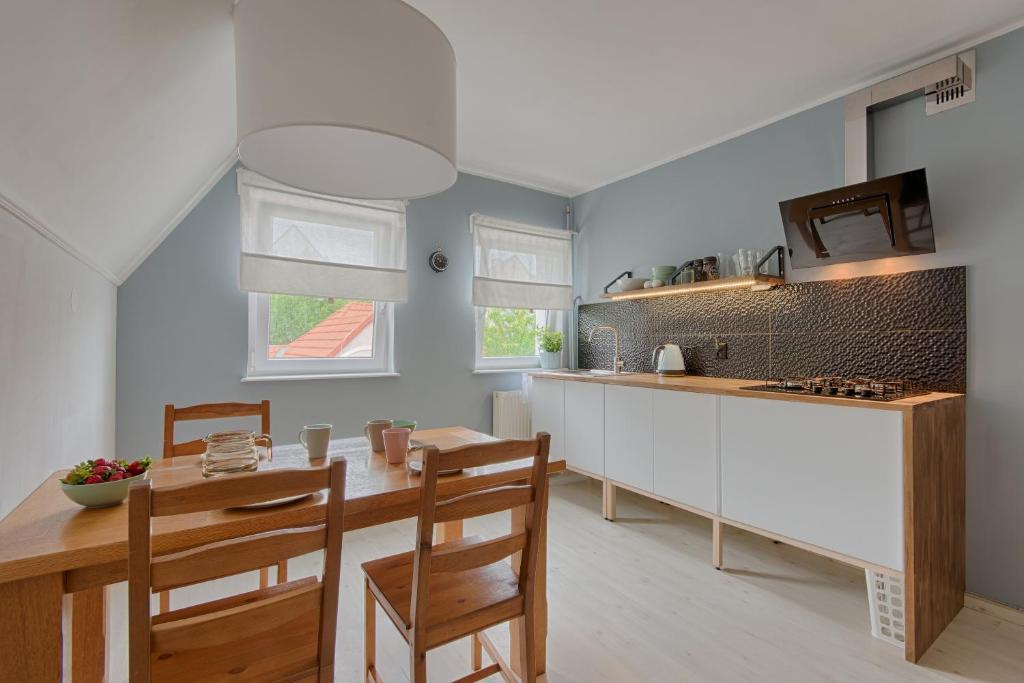 グダニスクにあるStary Gdańskの白いキャビネット、テーブルと椅子付きのキッチンが備わります。