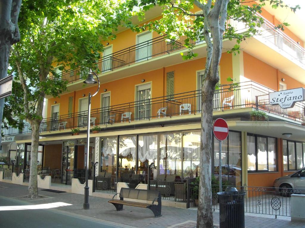 un edificio naranja con un banco delante de él en Albergo Santo Stefano, en Bellaria-Igea Marina