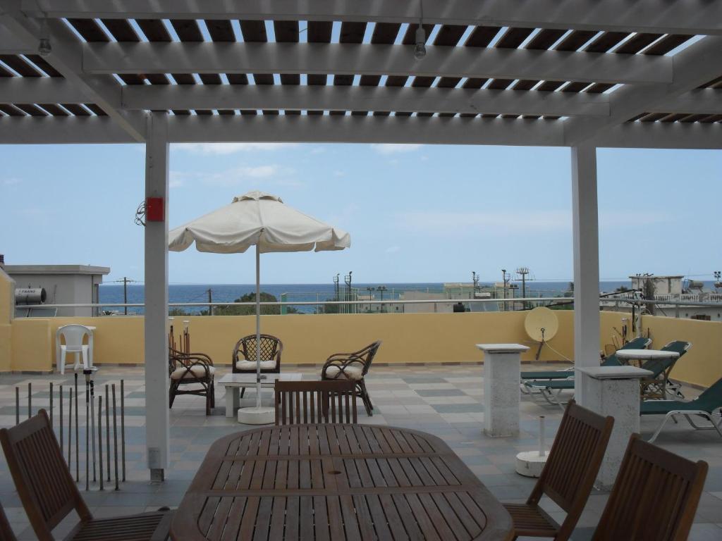 a patio with a table and chairs and an umbrella at La Santre Villa in Amoudara Herakliou