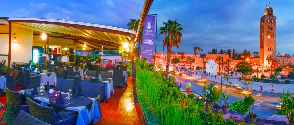 a restaurant with tables and chairs on a city street at Hotel Islane in Marrakech