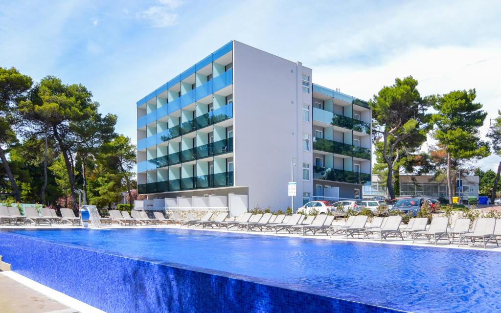 a hotel with a swimming pool in front of a building at Villas Arausana & Antonina in Vodice