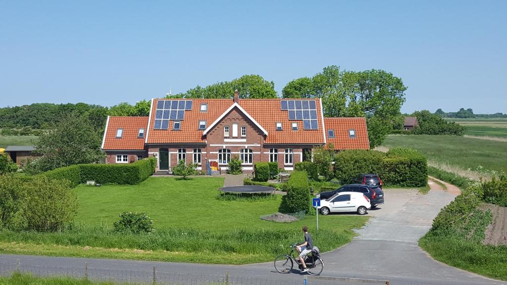 a person riding a bike in front of a house with solar panels at Ferienwohnungen Zollhaus Utlandshoern in Norden