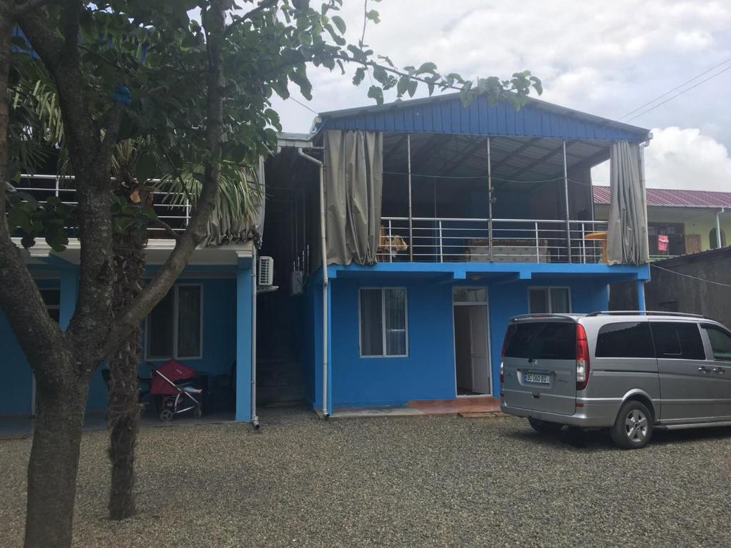 een busje geparkeerd voor een blauw huis bij Saba Guest House in Ureki