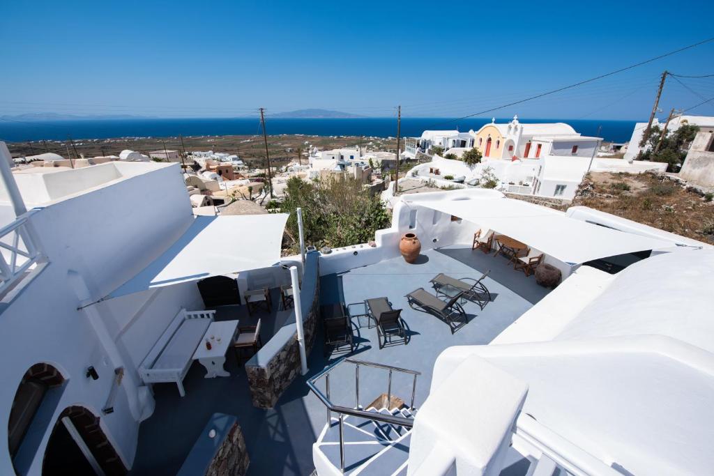 a view of a white building with chairs and tables at Caves 1880 in Oia