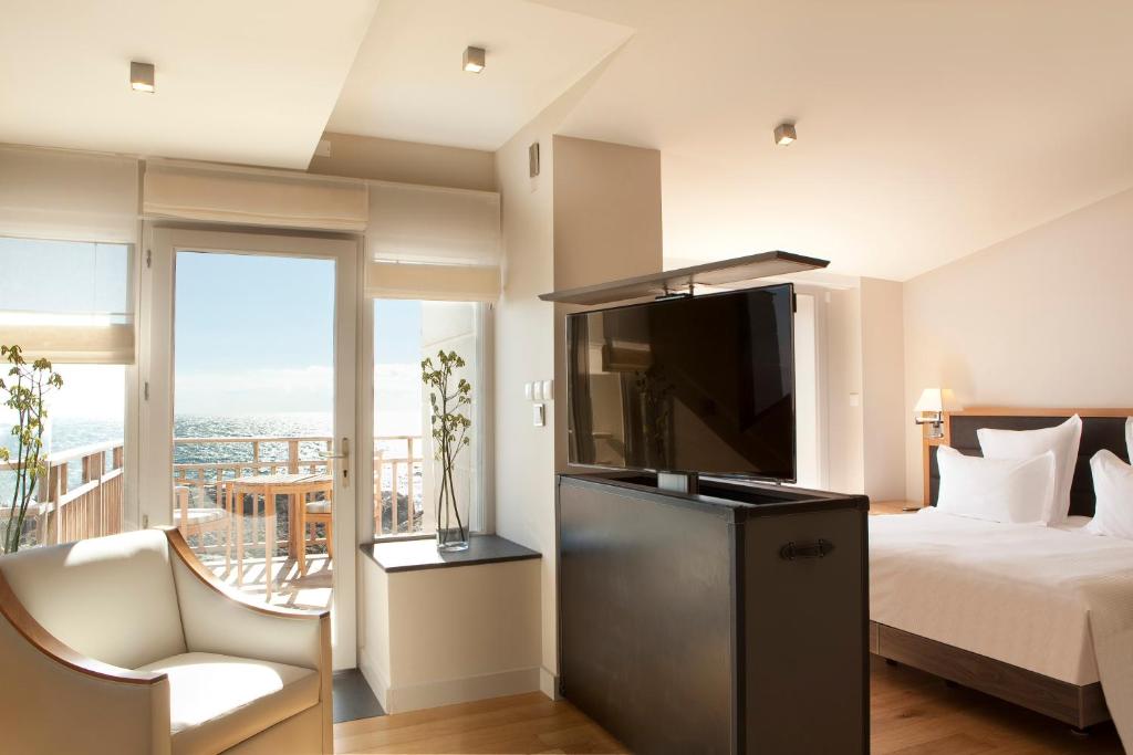 a bedroom with a bed and a television and a balcony at Grand Hotel de L'Océan in Le Croisic