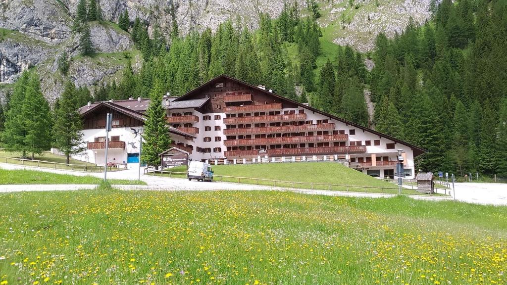 a large building in front of a field of flowers at Dolomites Dream Marmolada in Rocca Pietore
