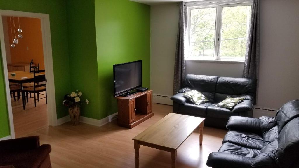een woonkamer met groene muren en een bank en een tv bij Appartement près des Plaines d'Abraham in Québec