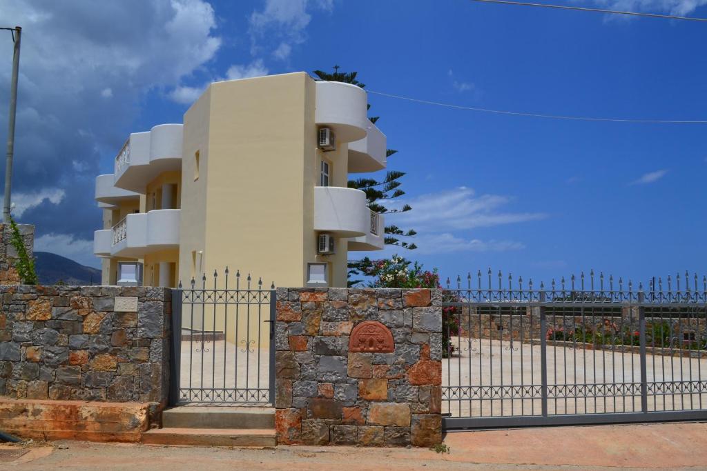 a white building behind a fence with a stone wall at Asteri apartments in Malia