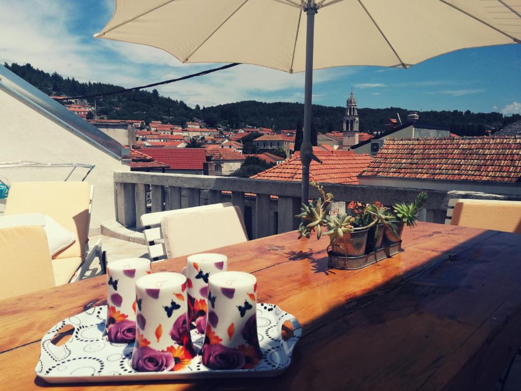 una mesa de madera con velas y una sombrilla en el balcón en Apartments Ani en Vela Luka
