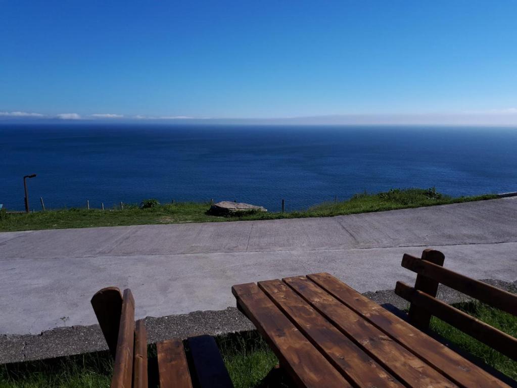 a wooden bench sitting on the side of the ocean at Old Irish farmhouse in Dingle