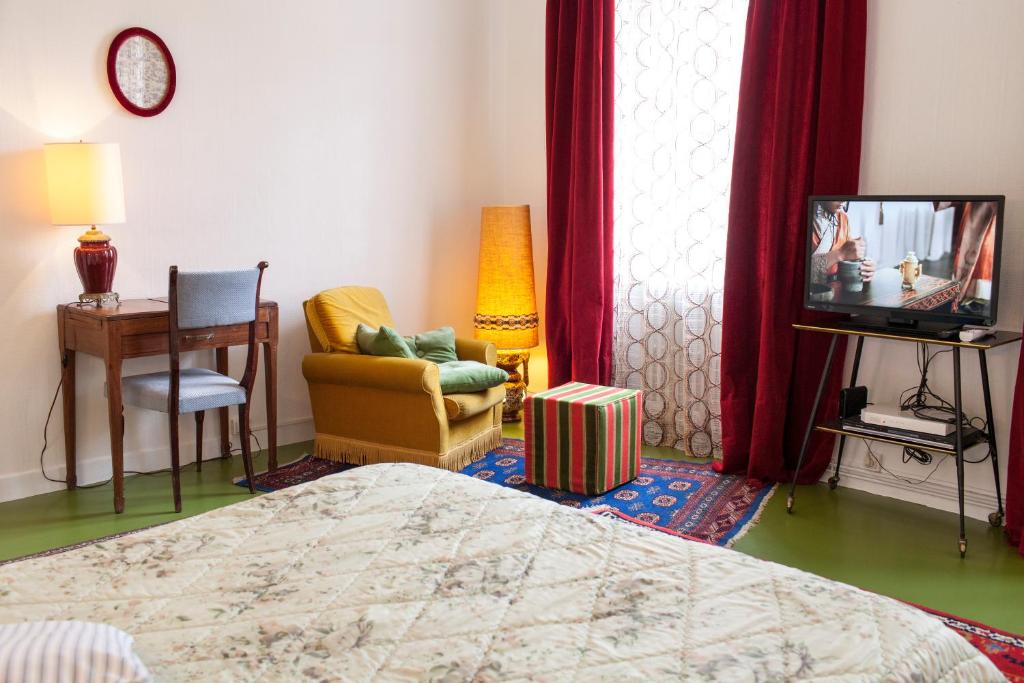 - une chambre avec un lit, une télévision et une chaise dans l'établissement 46FM : Montauban Guest House, à Montauban
