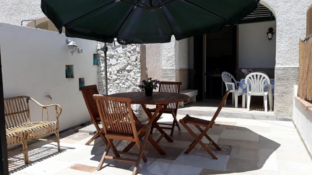 una mesa, sillas y una sombrilla en el patio en VILLINO DOLORES 30 MT MARE, en Porto Cesareo