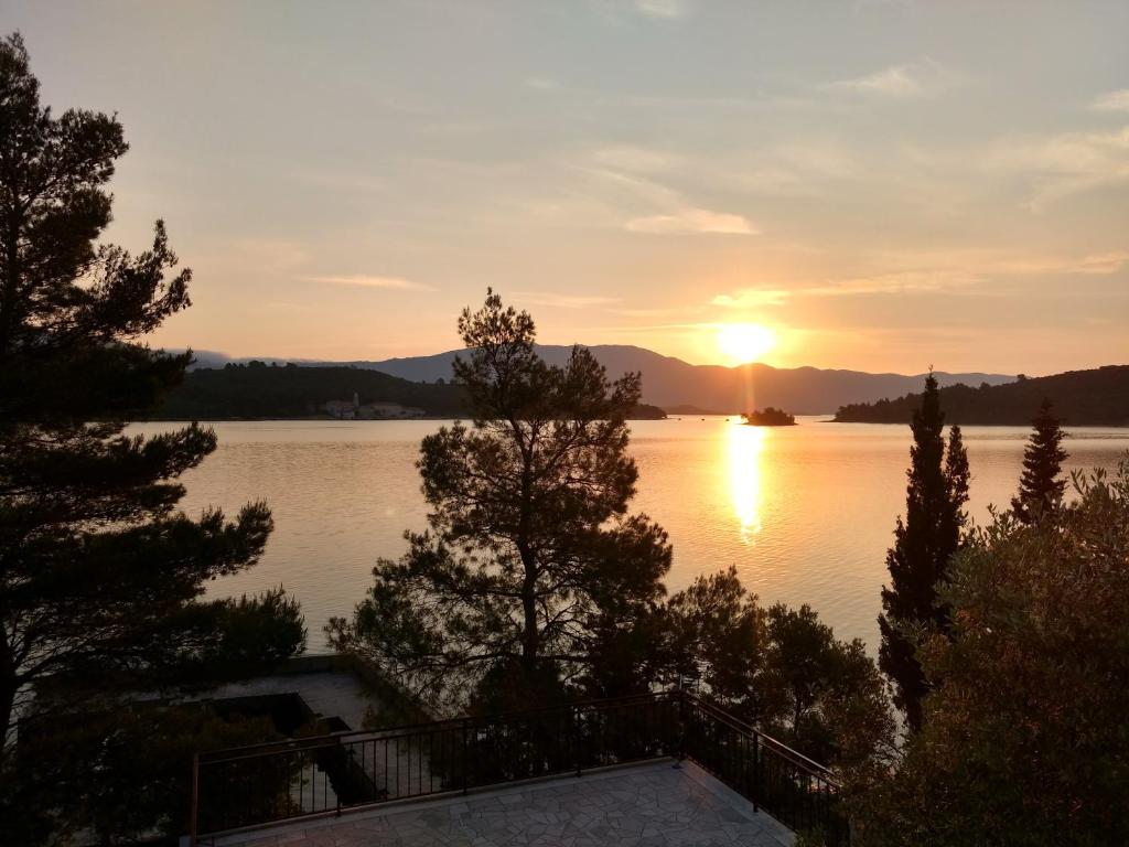 una puesta de sol sobre un lago con árboles en primer plano en Attic Katić, en Korčula