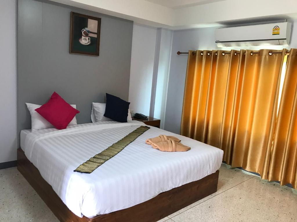 um quarto com uma cama com lençóis brancos e almofadas coloridas em @ RocKo Hotel em Uttaradit