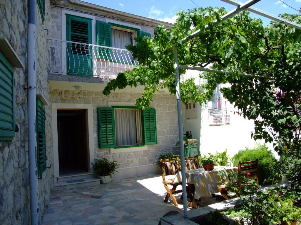 una casa con persianas verdes y una mesa frente a ella en Apartments Villa Rosa, en Split
