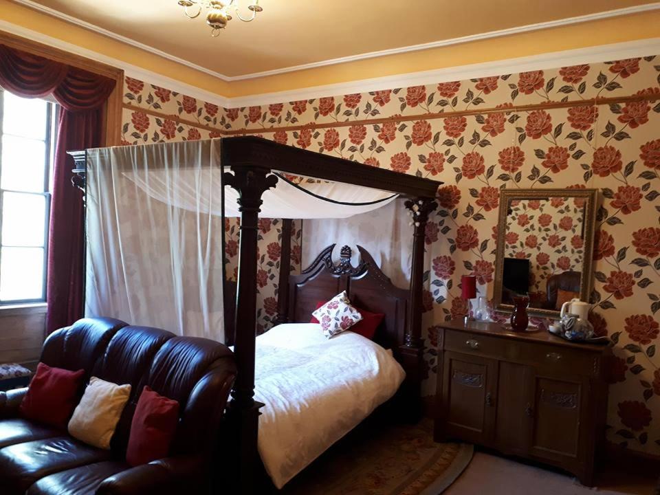 a bedroom with a canopy bed and a couch at Hallgreen castle in Inverbervie