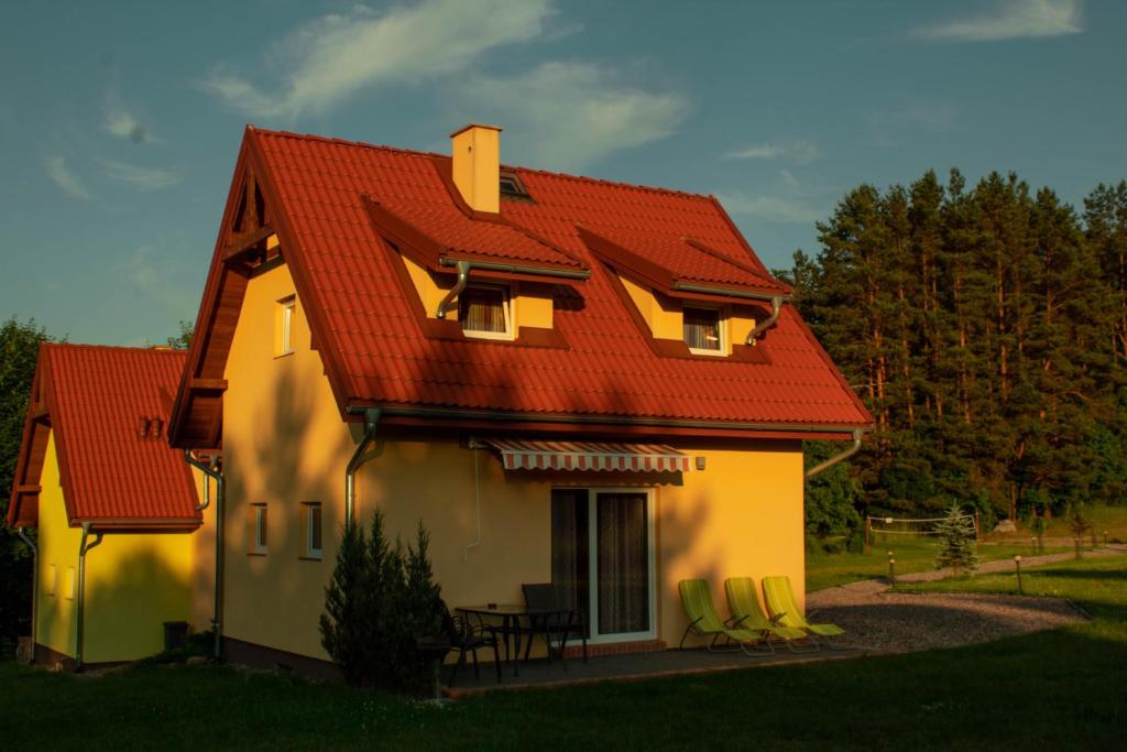 una casa con techo rojo y sillas verdes en Mazurski domek en Mrągowo